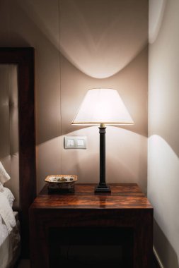 Üst yatak köşesinde zarif lamba yanan ile ahşap başucundaki