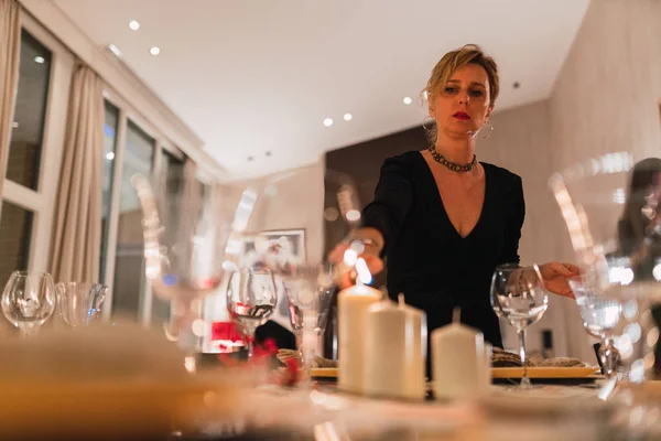 从下面的成年优雅的女人在桌子上点燃蜡烛 在晚上的节日晚餐 — 图库照片