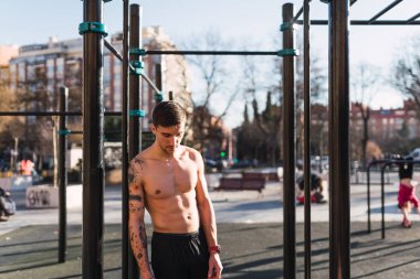 Genç sportif gömleksiz adam çene barlar açık spor salonunda kadar yakın güneşli bir günde dinlenme