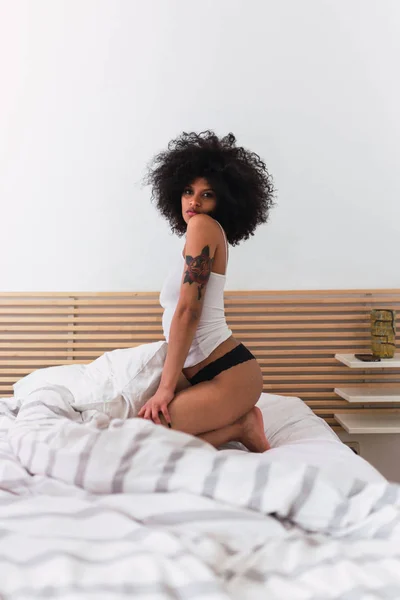 Czarujący młody czarny kobiety w bieliźnie pozowanie na łóżku — Zdjęcie stockowe