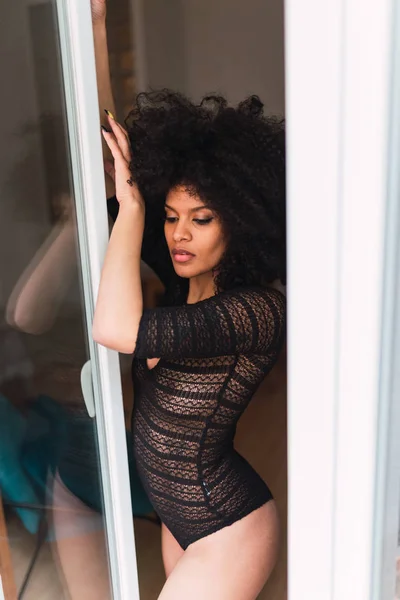 Молодая очаровательная черная женщина в телесном костюме позирует у окна — стоковое фото