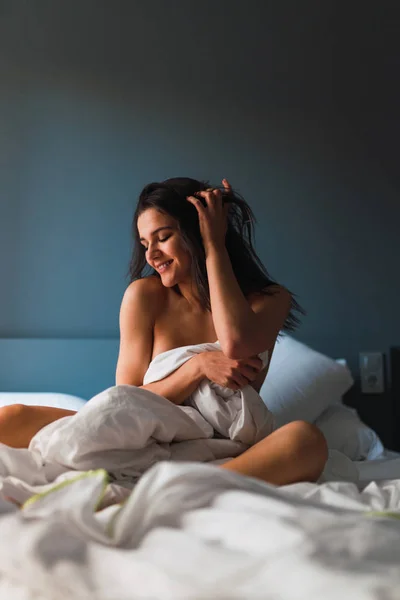 Jovem sorrindo mulher nua sentada na cama — Fotografia de Stock