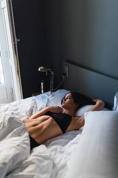 Молодая женщина в нижнем белье лежит на кровати — стоковое фото