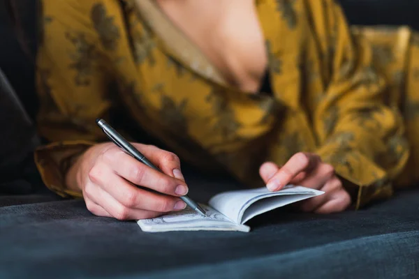 Jovem com caneta e caderno deitado no sofá — Fotografia de Stock