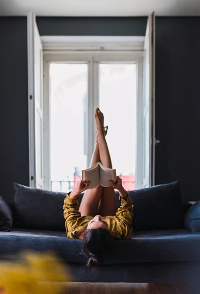 Young woman with book lying on sofa — Stock Photo, Image