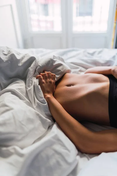 Тело молодой женщины в нижнем белье лежит на кровати — стоковое фото