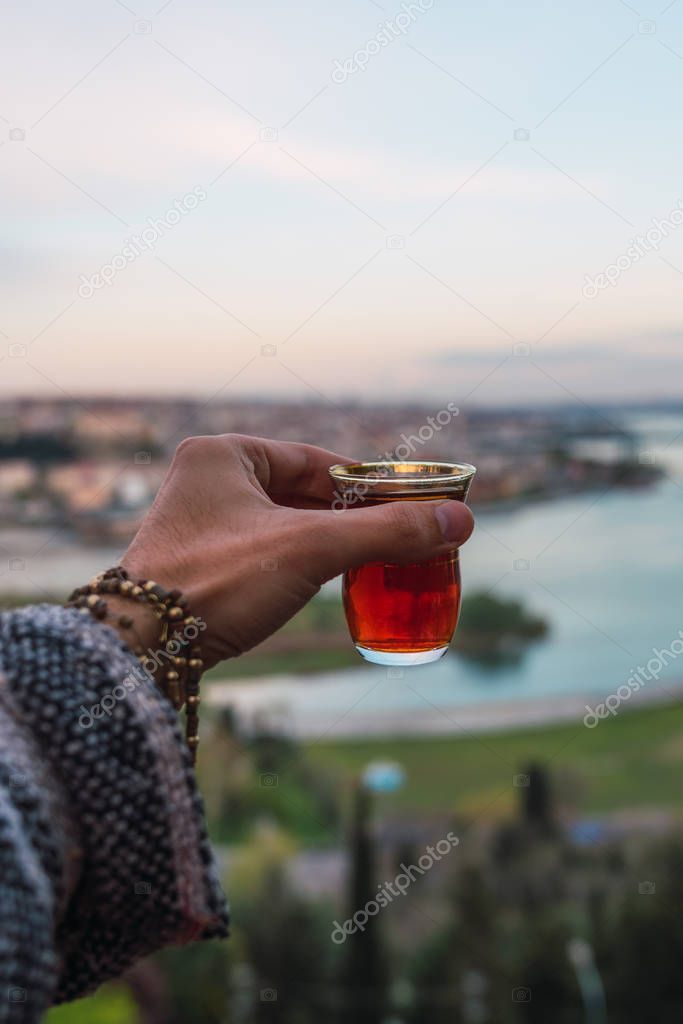 Hand holding red wine against Istanbul landscape