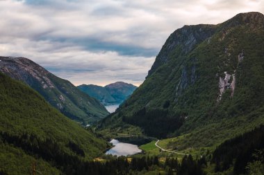 Sakin nehir ve yeşil dağların üzerinde bulutlu gökyüzü