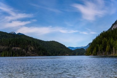 British Columbia 'da dağlarla çevrili güzel bir göl. Soğuk su gökyüzü kadar mavidir. Güzel beyaz bulutlar
