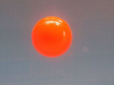 Grafik tasarımı ya da illüstrasyon fotoğrafı için koyu gri desenli arka planda izole edilmiş tek bir turuncu plastik top görüntüsü. renkler