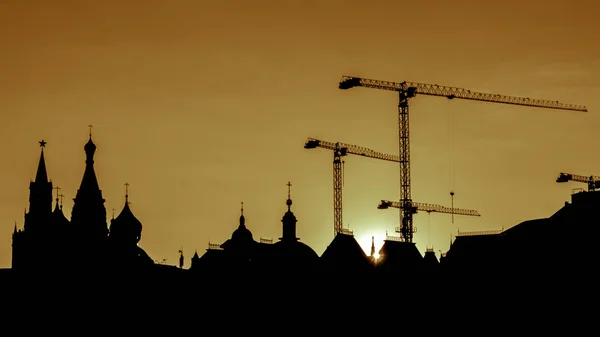 Kızıl Meydan kuleleri ve gün batımında Moskova'da İnşaat vinçleri kıvrımlarına