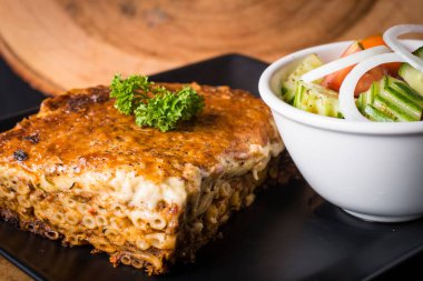 Pastitsio Yunan usulü peynirli makarna salatayla servis edilir.
