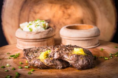 Biftek, patates püresi ve erimiş tereyağlı sos ile servis edilir.