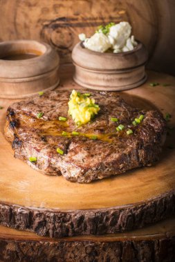Biftek, patates püresi ve erimiş tereyağlı sos ile servis edilir.