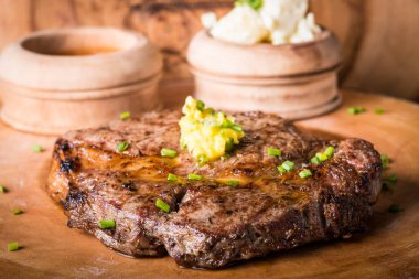 Biftek, patates püresi ve erimiş tereyağlı sos ile servis edilir.