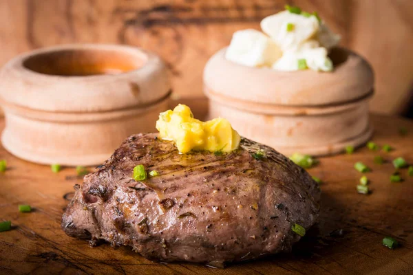 Biftek, patates püresi ve erimiş tereyağlı sos ile servis edilir.