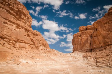 Mavi gökyüzü, kumlu güneş ve dağlı çöl manzarası.