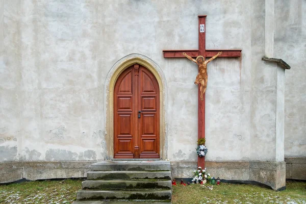 Puerta de madera a la iglesia y una gran cruz en la pared. Velas encendidas. Tradición cristiana . — Foto de Stock