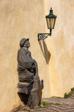 Merdivenlerde bir müzisyen heykeli ve Prag Kalesi 'nde gölgesi olan bir fener.