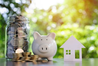 Piggy Bank ve ev modeliyle bozuk para yığını. Konut satın alma kredileri. Finansal büyüme kavramından tasarruf. İleride işletme finansmanına hazırlanmak için para biriktir.