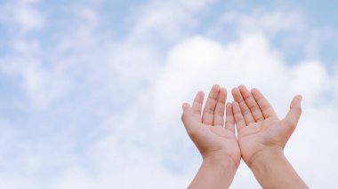 The hand of a woman praying worship for the blessing of god against the sky background. Hands open palm up clipart