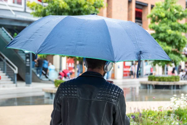 A man seeking shelter from the rain whilst out shopping