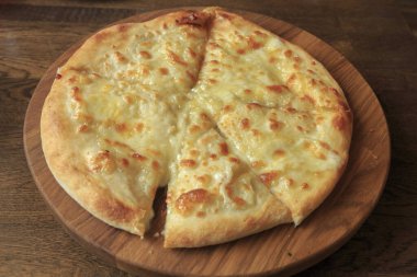 Masadaki ahşap tabakta taze peynirli pizza İtalyan geleneksel aperatifi, yüksek açı manzaralı..