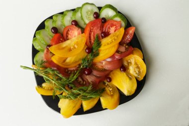 Vejetaryen yemeği. Domatesli salata, salatalık ve siyah tabakta dereotu. Beyaz arkaplanda izole