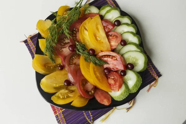 Vejetaryen yemeği. Domatesli salata, salatalık ve siyah tabakta dereotu. Beyaz arkaplanda izole