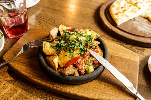 Restoran Vuruşu. Patates ve sebzeyle pişirilmiş sıcak tavada et. Kafkas mutfağı.