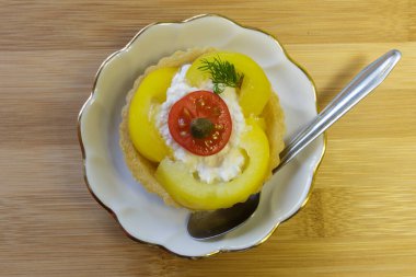 Süzme peynir, sebze ve kapari salatalı çıtır tartlar. Beyaz tabak. Ahşap arkaplan.