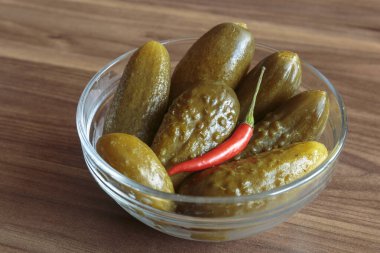 Ahşap arka planda kırmızı biberli salatalık turşusu. Lezzetli atıştırmalıklar, vejetaryen yemekleri..