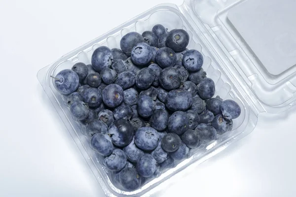 Blueberry in a plastic packaging on a white background, ready to sell, Vegan food. Business concept.