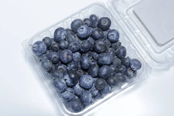 Beyaz arka planda plastik ambalajlı yabanmersini satılmaya hazır, vejetaryen yemeği. İş konsepti.