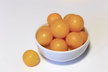 Beyaz tabakta çiğ sarı kiraz domatesleri yakın plan, yemeye hazır, beyaz, vejetaryen yiyeceklere izole edilmiş..