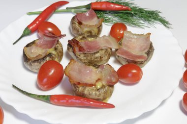 Pastırma ve peynirle doldurulmuş mantarlar, beyaz arka planda izole edilmiş, yemeye hazır beyaz bir tabakta..