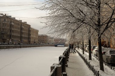 Güneşli bir günde Moika nehrinin donmuş seti, buzlu ağaçlar ve nehir üzerindeki patikalar..