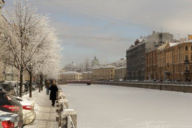 Güneşli bir günde Moika nehrinin donmuş seti, buzlu ağaçlar ve nehir üzerindeki patikalar..