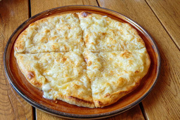 Fresh cheese pizza on a plate on the table, Italian traditional appetizer, high angle view.