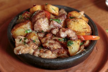 Kızartma tavasında et, patates, sebze ve otlarla..