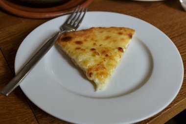 Lokantada beyaz tabakta dilimlenmiş peynirli pizza, İtalyan geleneksel aperatifi..