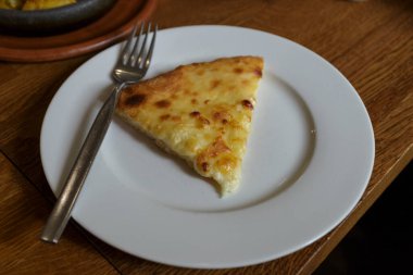 Lokantada beyaz tabakta dilimlenmiş peynirli pizza, İtalyan geleneksel aperatifi..