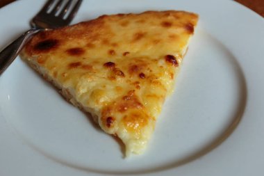 Lokantada beyaz tabakta dilimlenmiş peynirli pizza, İtalyan geleneksel aperatifi..