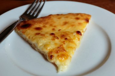 Lokantada beyaz tabakta dilimlenmiş peynirli pizza, İtalyan geleneksel aperatifi..