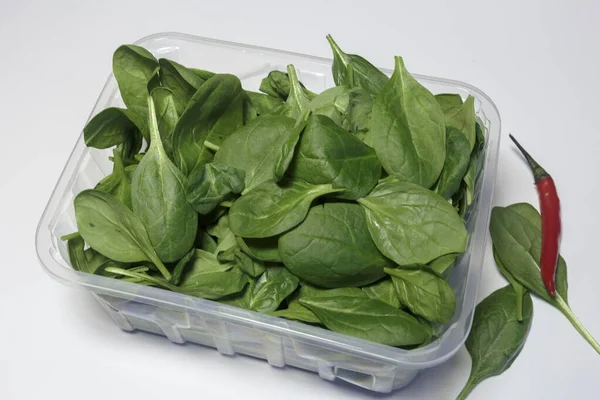 Spinach in a plastic packaging on a white background, ready to sell, Vegan food. Business concept.