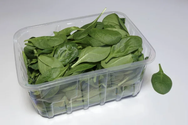 Spinach in a plastic packaging on a white background, ready to sell, Vegan food. Business concept.