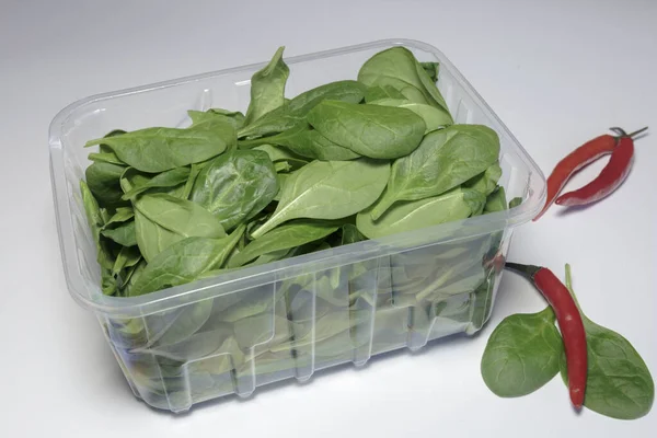 Spinach in a plastic packaging on a white background, ready to sell, Vegan food. Business concept.