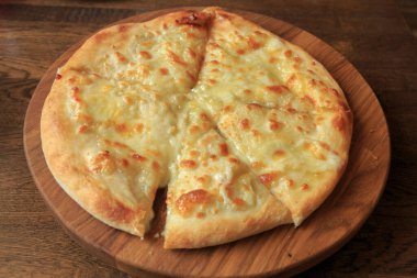 Masadaki ahşap tabakta taze peynirli pizza İtalyan geleneksel aperatifi, yüksek açı manzaralı..