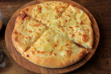 Masadaki ahşap tabakta taze peynirli pizza İtalyan geleneksel aperatifi, yüksek açı manzaralı..