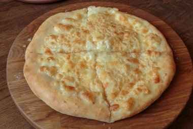 Masadaki ahşap tabakta taze peynirli pizza İtalyan geleneksel aperatifi, yüksek açı manzaralı..
